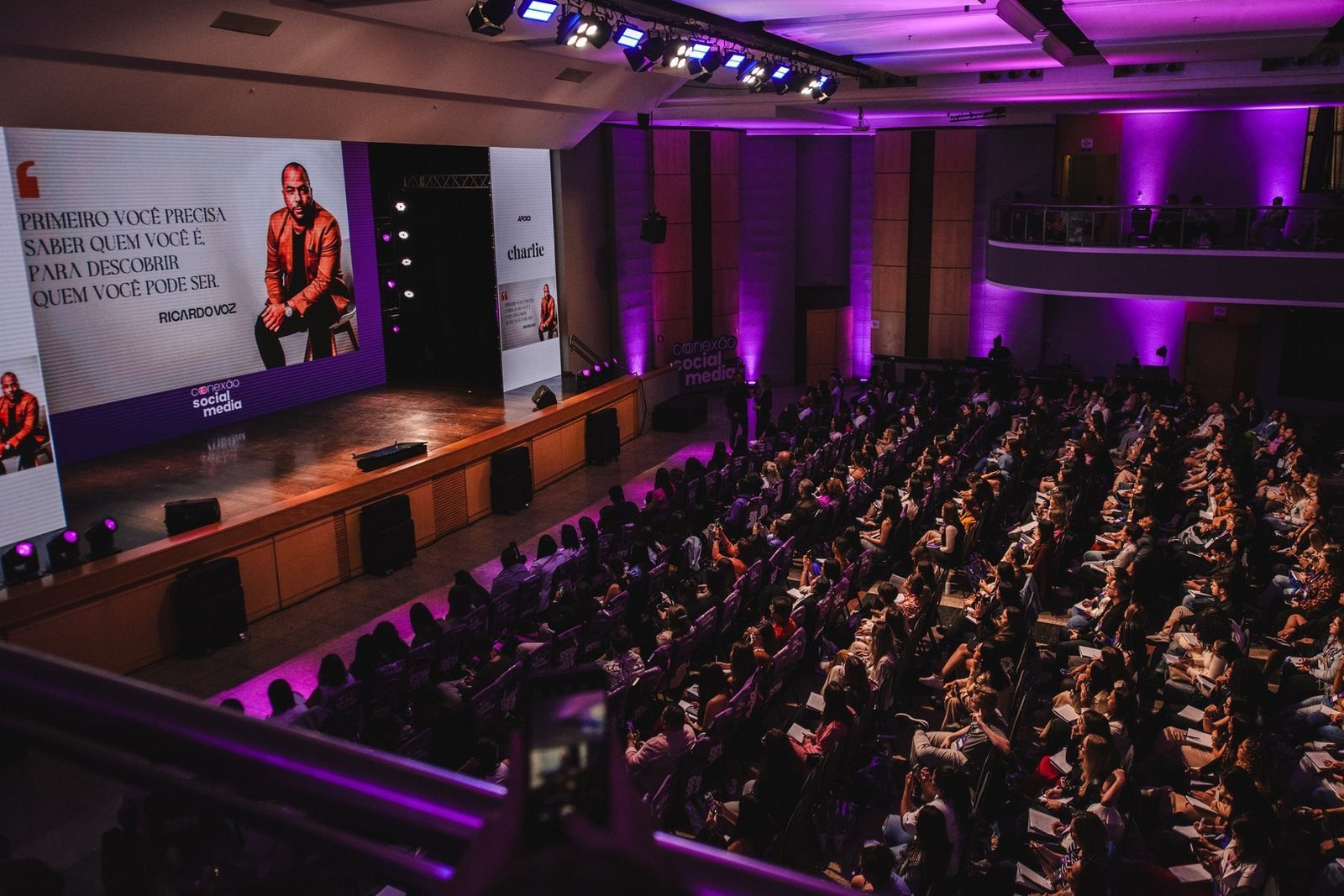 Ricardo Voz em auditório lotado, com seu nome no telão